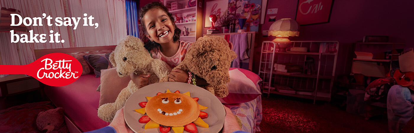 happy girl with missing tooth, holding two teddy bears & plate with a pancake