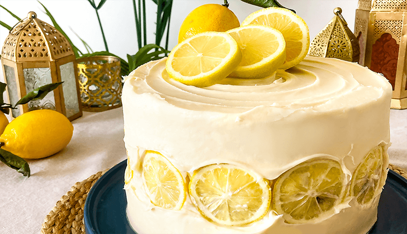 Bright lemon cake served on blue plate with lemon slice toppings