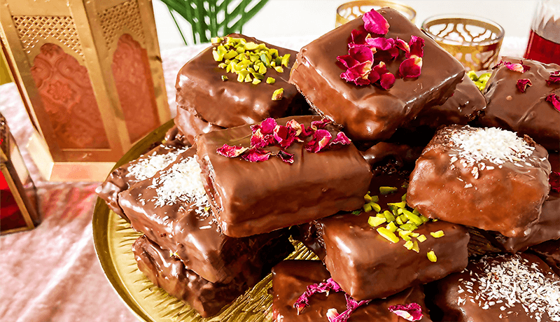 chocolate covered brownies served on golden colored plate garnished with rose petals and pistachios